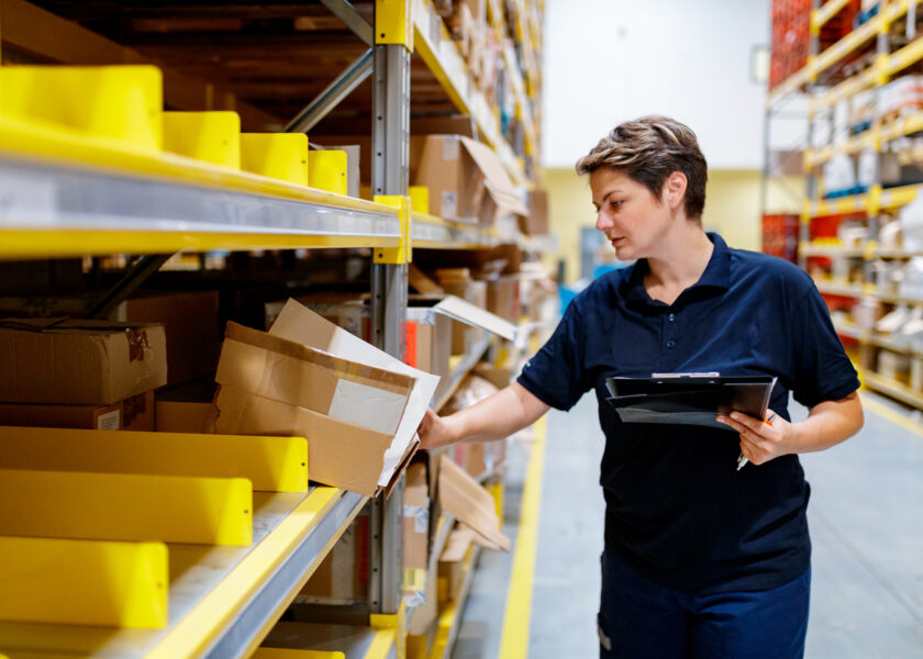 Warehouse worker holding checklist and checking content of box